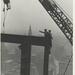 Two-construction-workers-at-the-corner-of-two-steel-beams-pointi